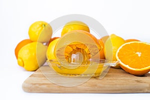 Squeezes fresh oranges with a juicer. Orange juice in a glass close to half of sliced Ã¢â¬â¹Ã¢â¬â¹oranges on a white background.